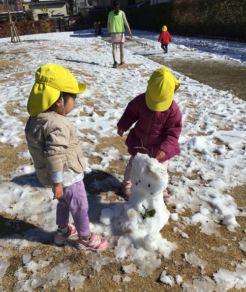 この雪だるまはなんだろう？と不思議そうに覗く子どもたち。葉っぱや枝などの飾りつけもしてあげていました。.jpg